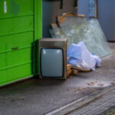 Garbage container with bags, glass and an old television on the floor